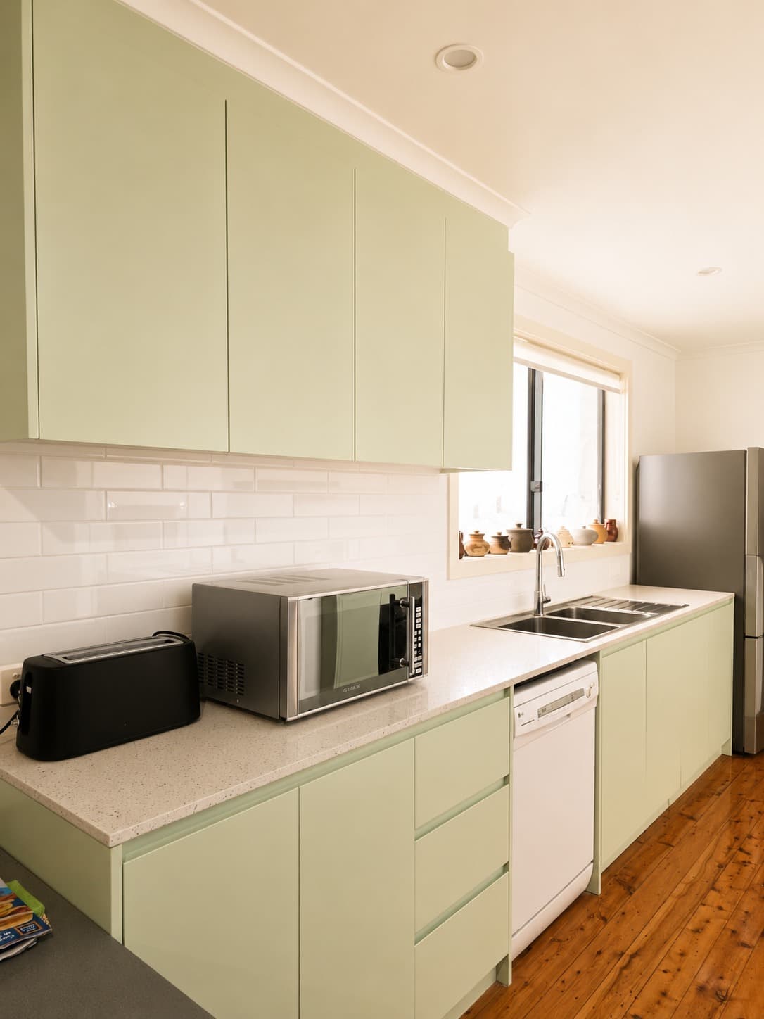 Sage green galley kitchen with white subway tile splashback