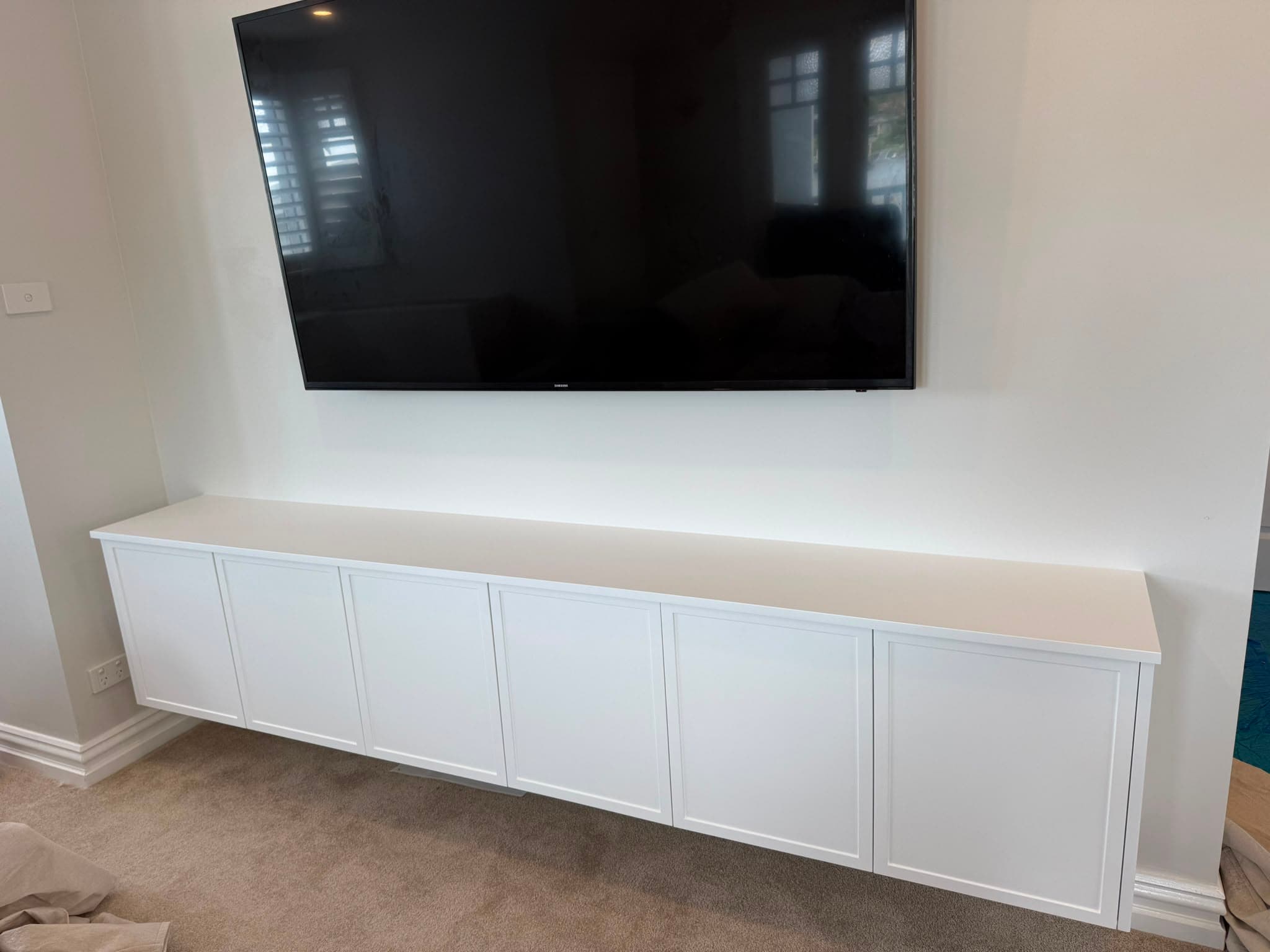 Floating white shaker media unit beneath a wall-mounted TV