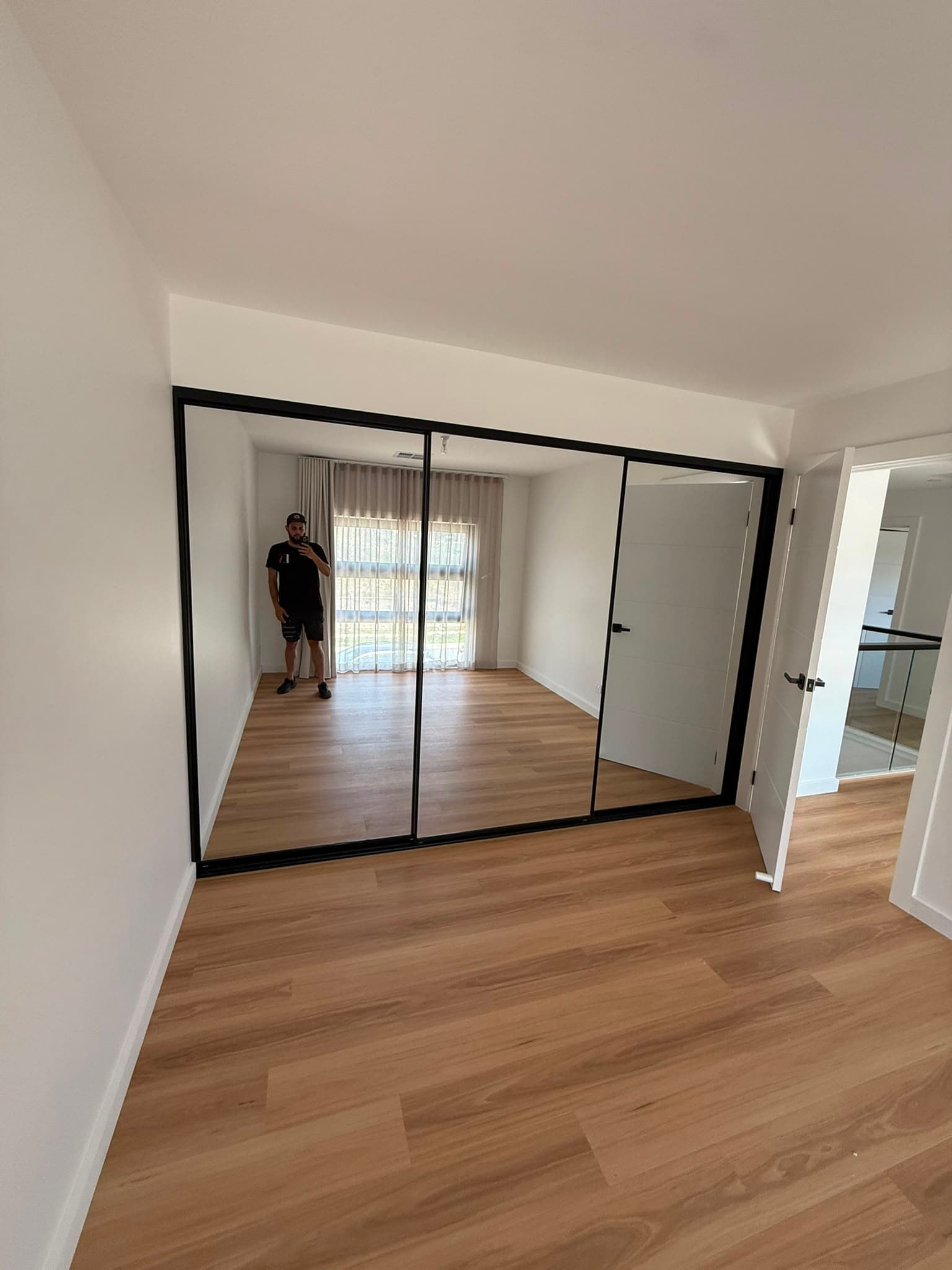 Black-framed mirrored sliding wardrobe doors in a bedroom
